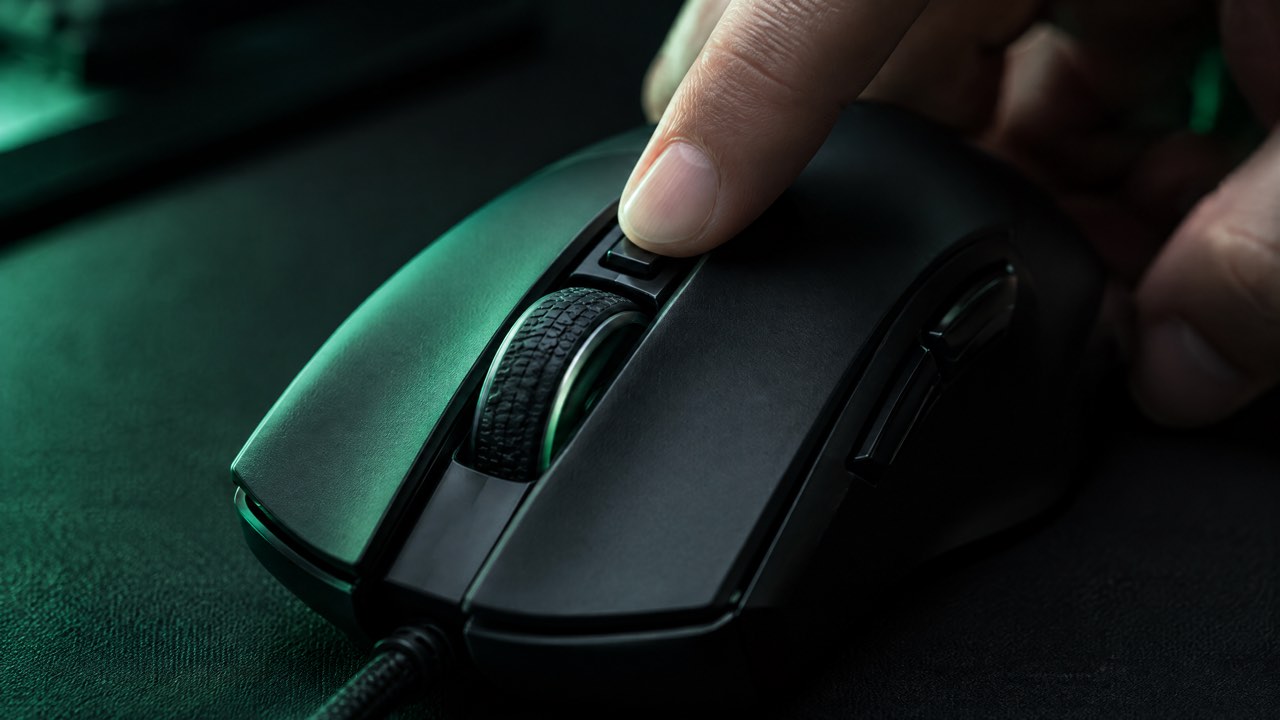 A finger pressing the DPI button on a gaming mouse